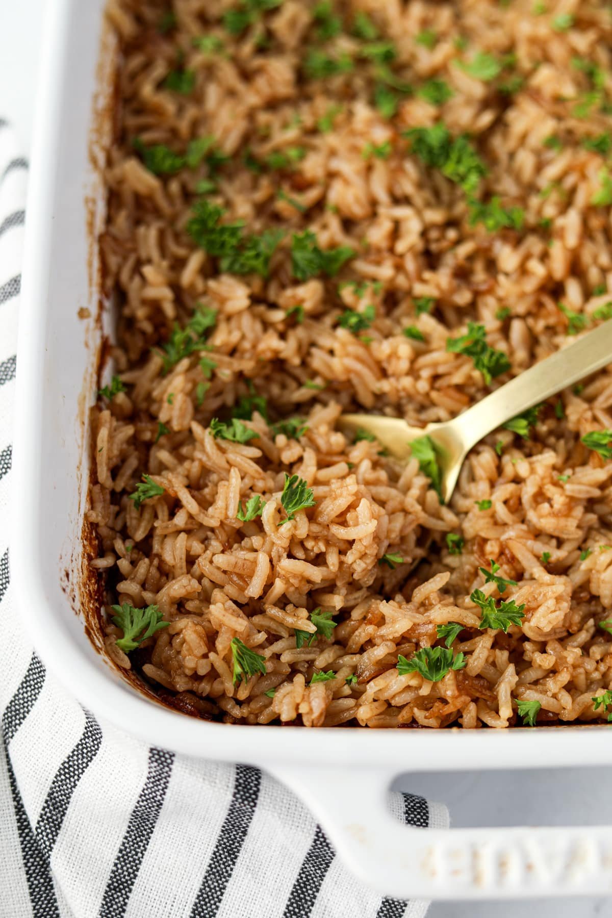 Scooping a pile of fluffy rice from a baking dish.