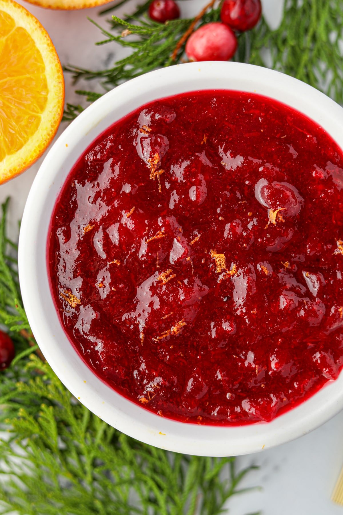 A small bowl of jelled cranberry sauce garnished with orange zest.