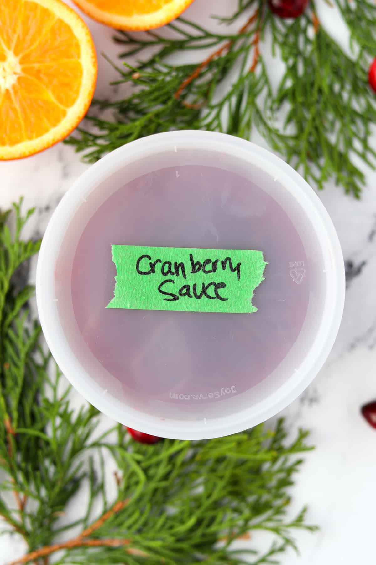 A deli container labeled "cranberry sauce", containing homemade cranberry sauce.