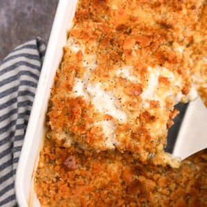 Lifting a portion of creamy casserole from a baking dish.