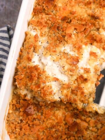 Lifting a portion of creamy casserole from a baking dish.