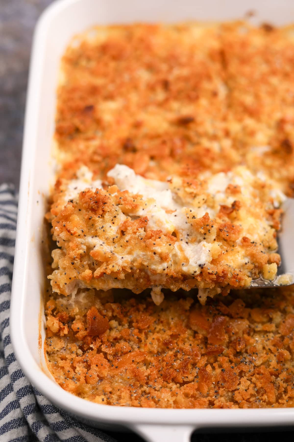 Lifting a portion of poppy seed chicken from a baking dish.