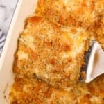 Lifting creamy chicken casserole from a baking dish using a spatula.