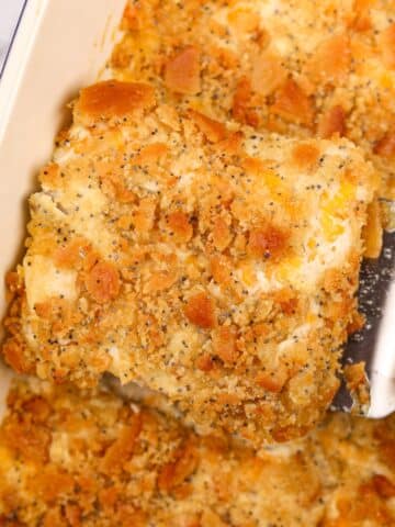 Lifting creamy chicken casserole from a baking dish using a spatula.