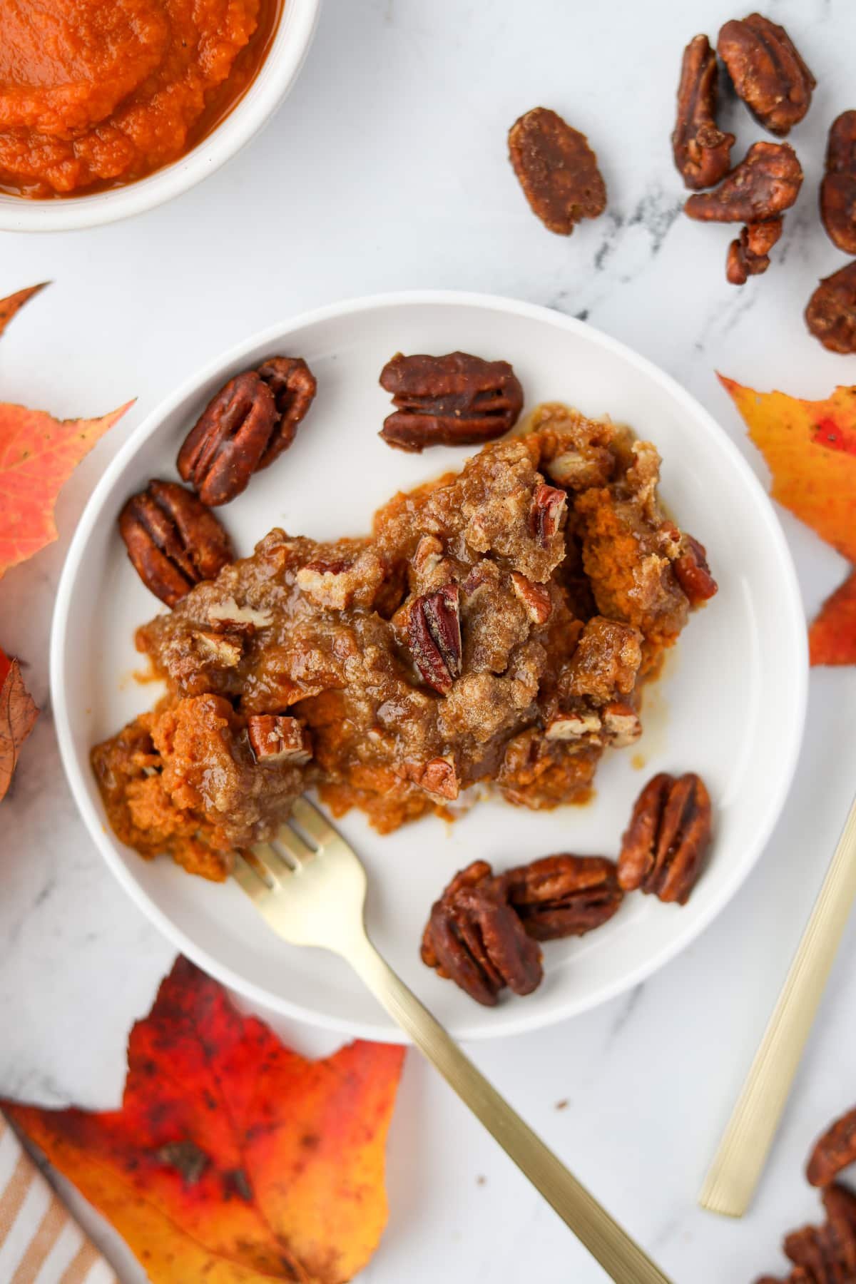 A plate with a scoop of pumpkin casserole topped with pecans.