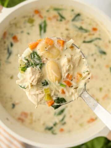 A ladle full of creamy soup being lifted from a pot.