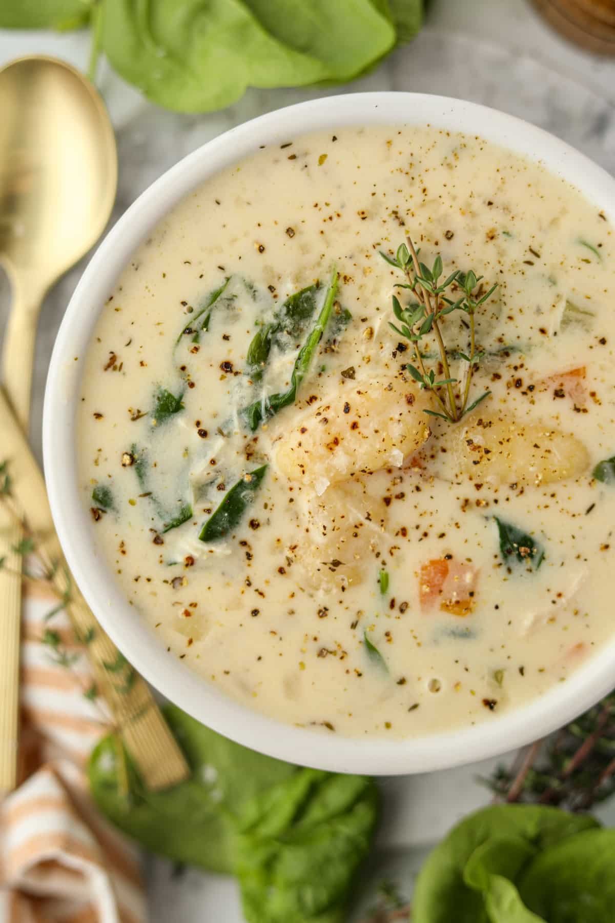 A bowl of creamy turkey soup garnished with fresh thyme.