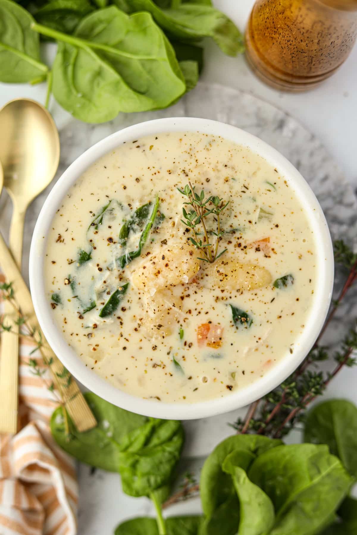 A bowl of cream soup garnished with black pepper and thyme.