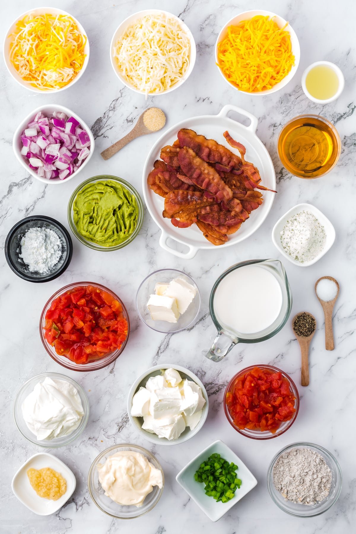 The ingredients needed to make a chip and dip board, including cream cheese, bacon, sour cream, shredded cheese, etc.