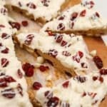 A triangular cranberry bliss bar topped with dried cranberries and cream cheese frosting.