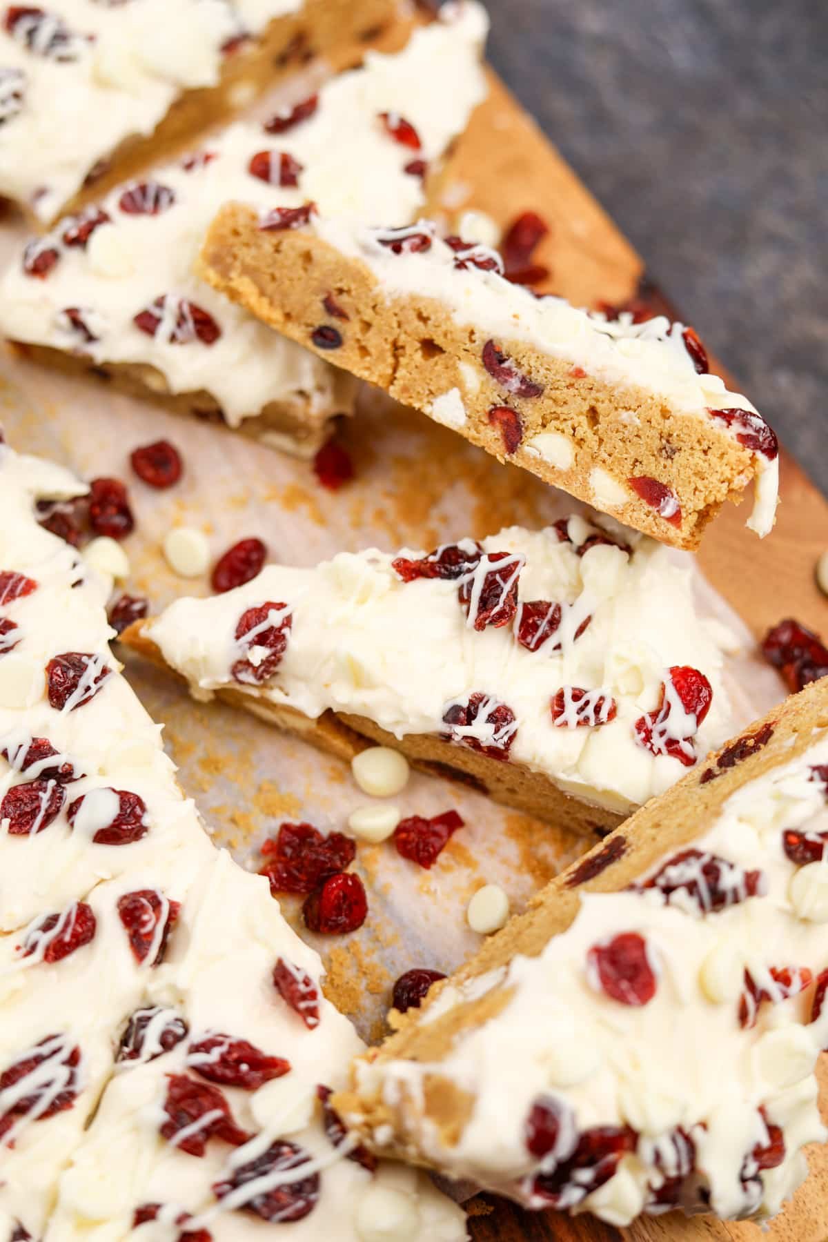 A side view of a homemade cranberry bliss bar, showing the white chocolate and cranberry dotted interior.