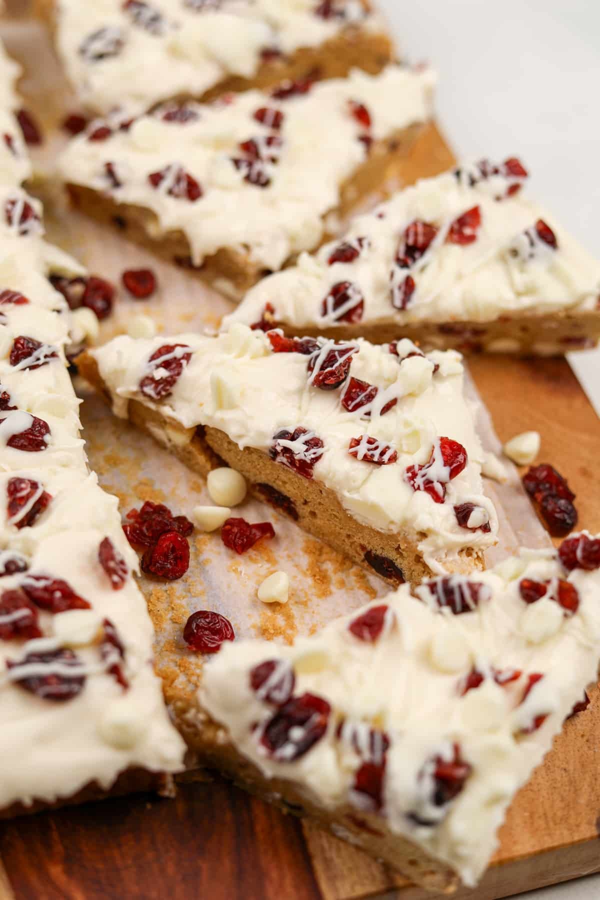 Triangle cookie bars topped with cream cheese frosting and dried cranberries.