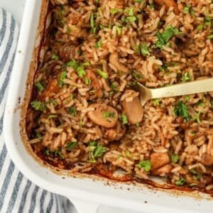 A spoon taking a portion of mushroom rice from a baking dish.