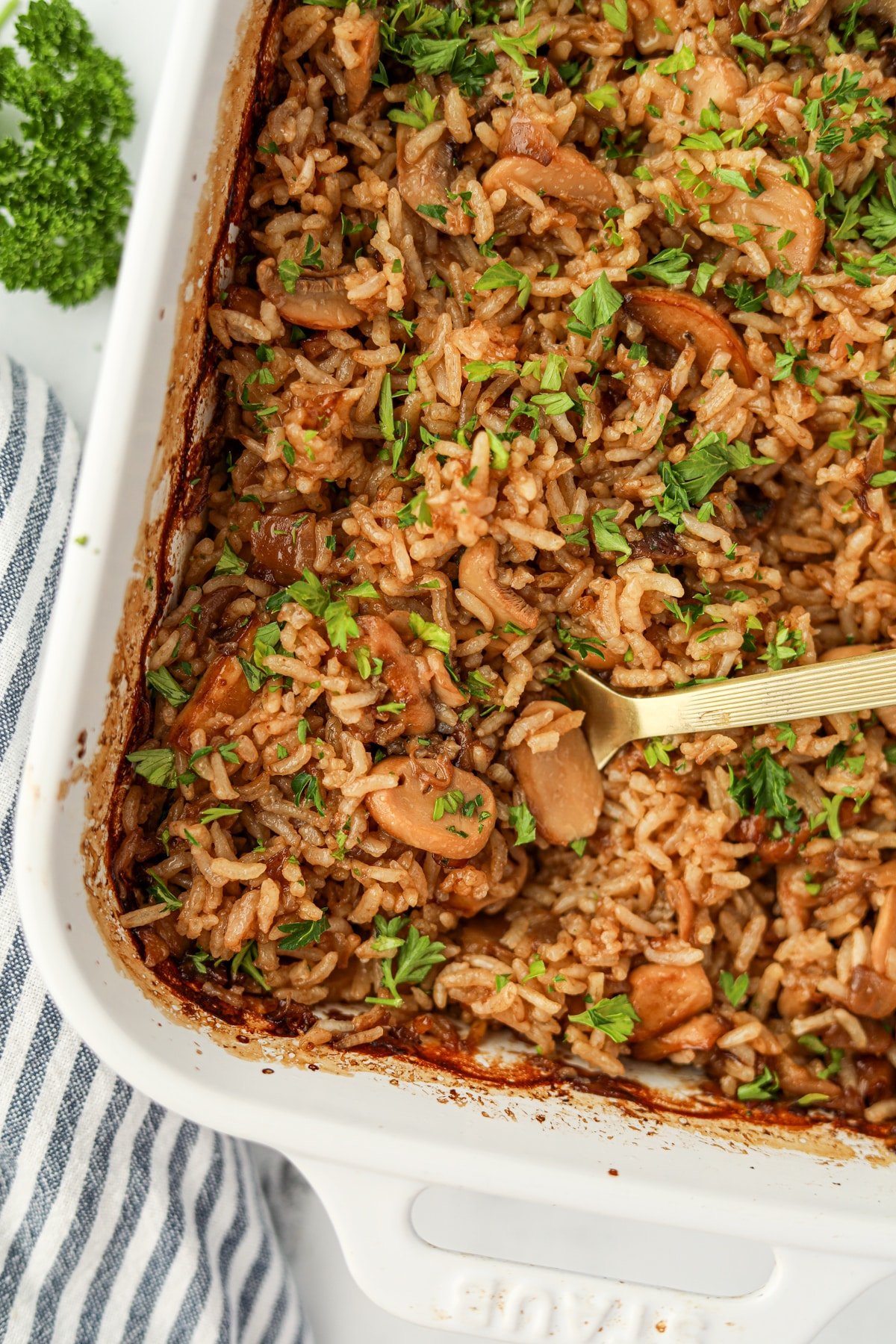 A spoon scooping into a rice casserole featuring mushrooms.