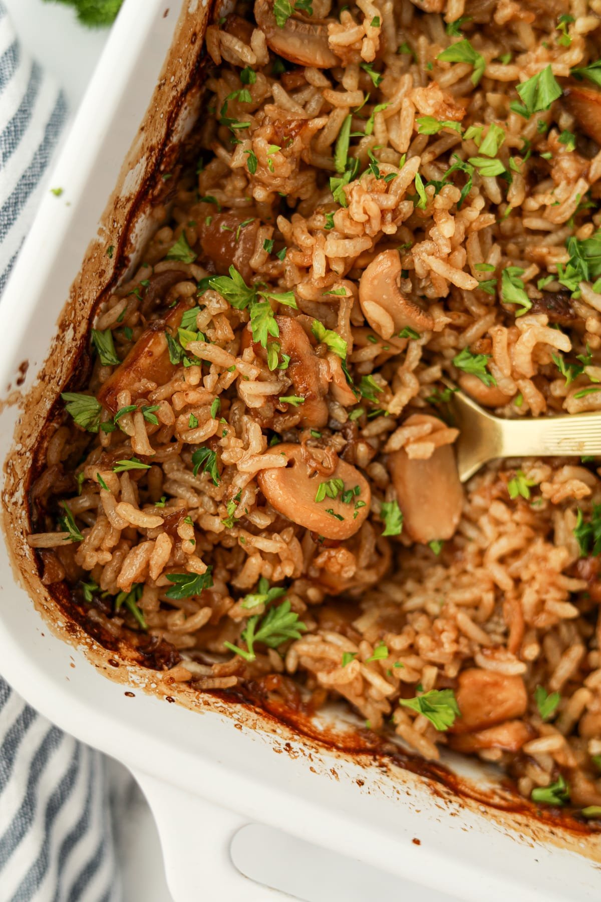 A spoon scooping a portion of mushroom rice from a baking dish.