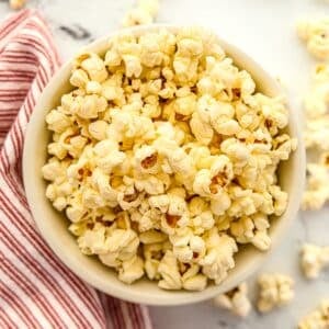 A bowl of buttery popcorn on a marble background.