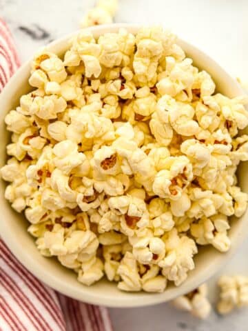 A bowl of buttery popcorn on a marble background.