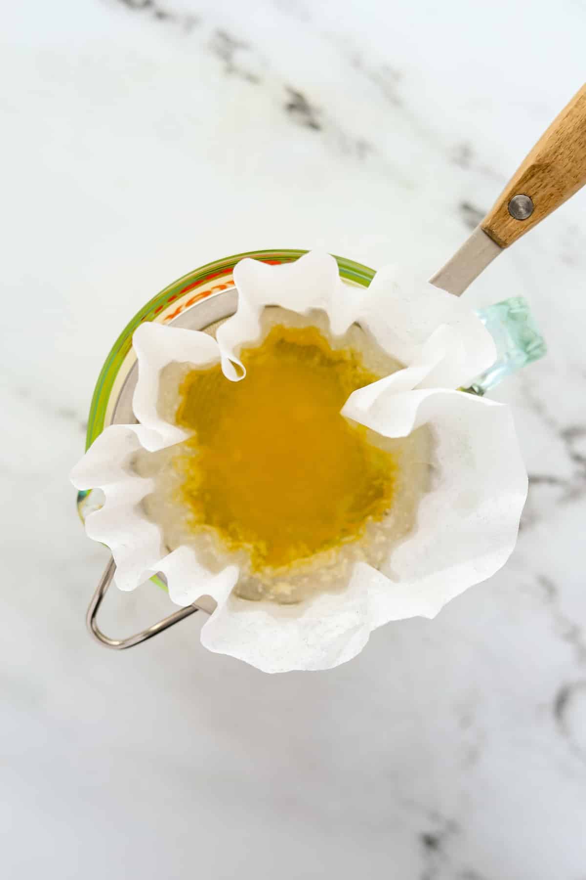 Straining butter through a coffee filter-lined strainer.
