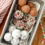 A loaf pan filled with three different types of truffles: one with cocoa, one with powdered sugar, and one with crushed candy canes.