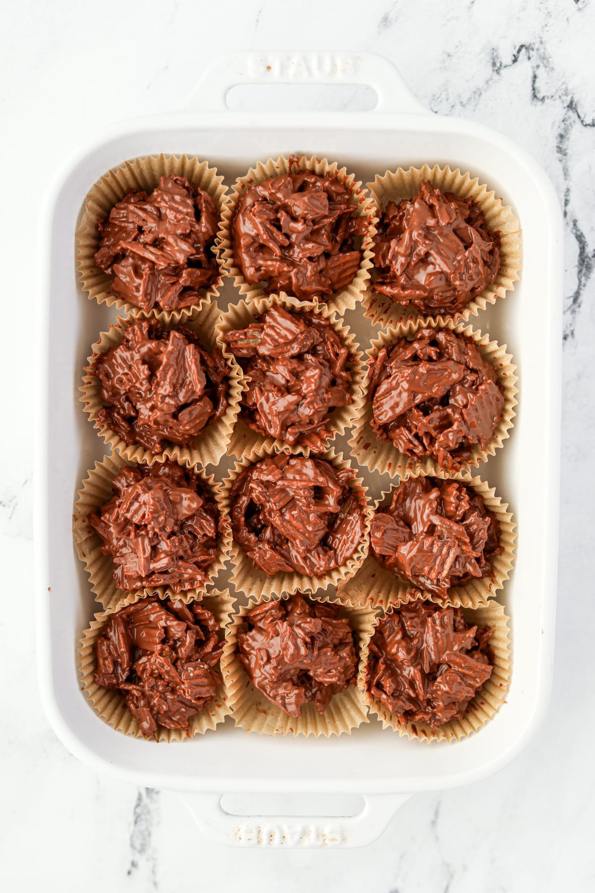 A baking dish filled wtih chocolate clusters in muffin liners.