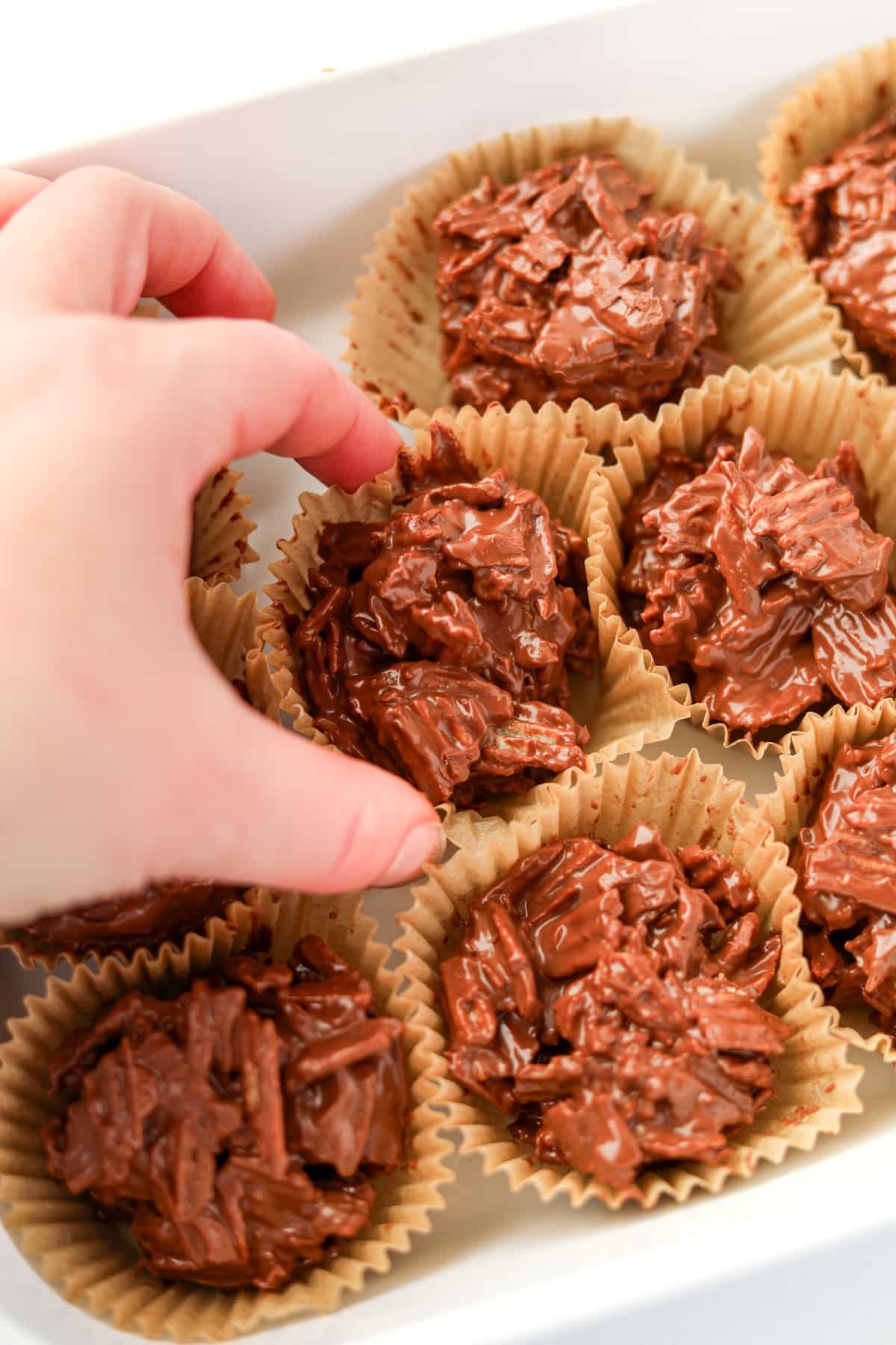 Taking a chocolate cluster from a baking dish.