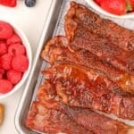 A stack of glazed bacon slices piled on top of a wire rack.