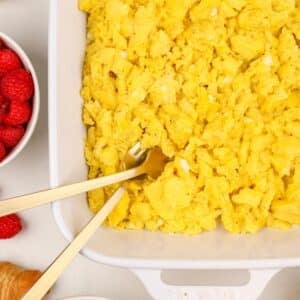 A white baking dish filled with cooked scrambled eggs.