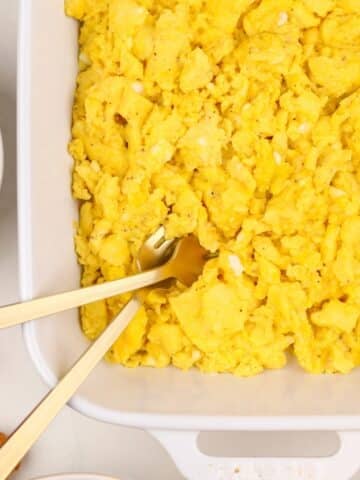 A white baking dish filled with cooked scrambled eggs.