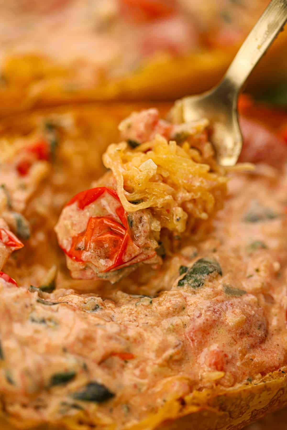 A fork twirling shredded spaghetti squash tossed with a creamy tomato sauce.