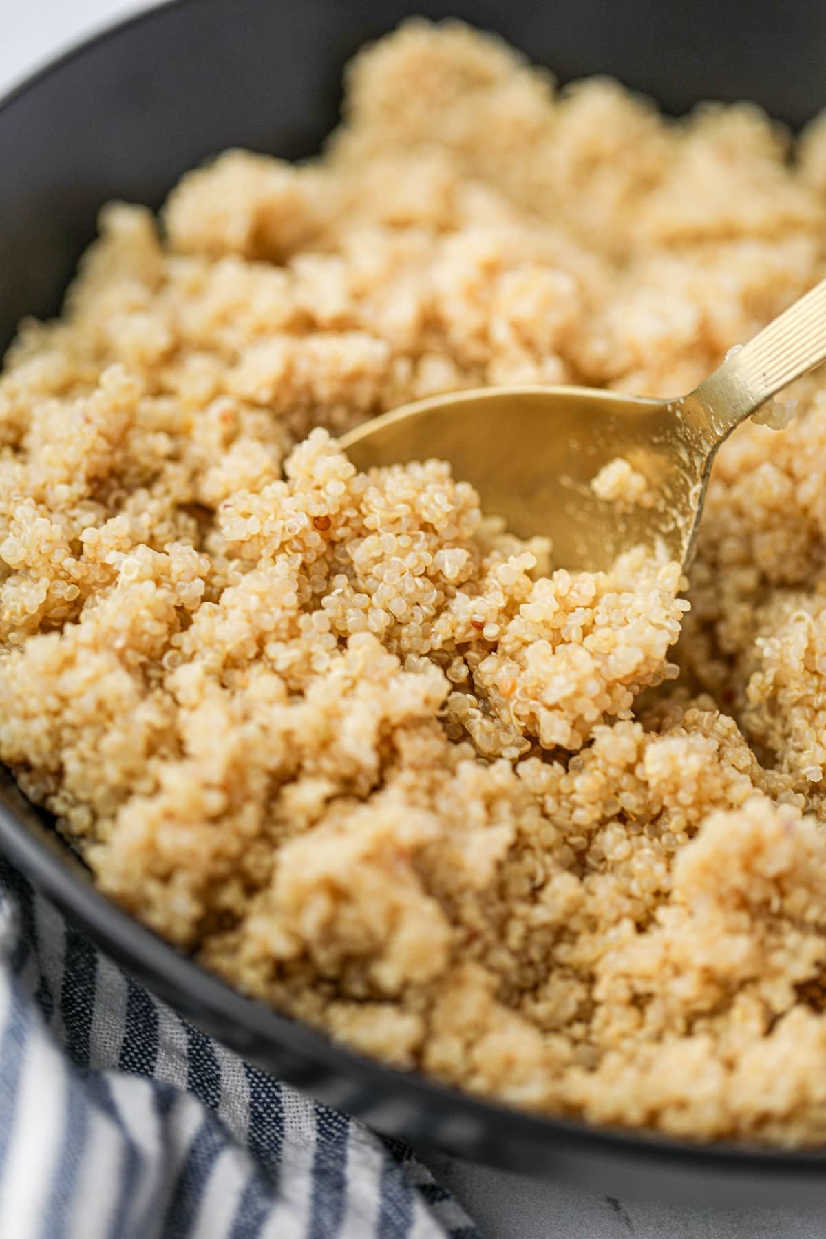 A close up of cooked quinoa on a golden spoon.