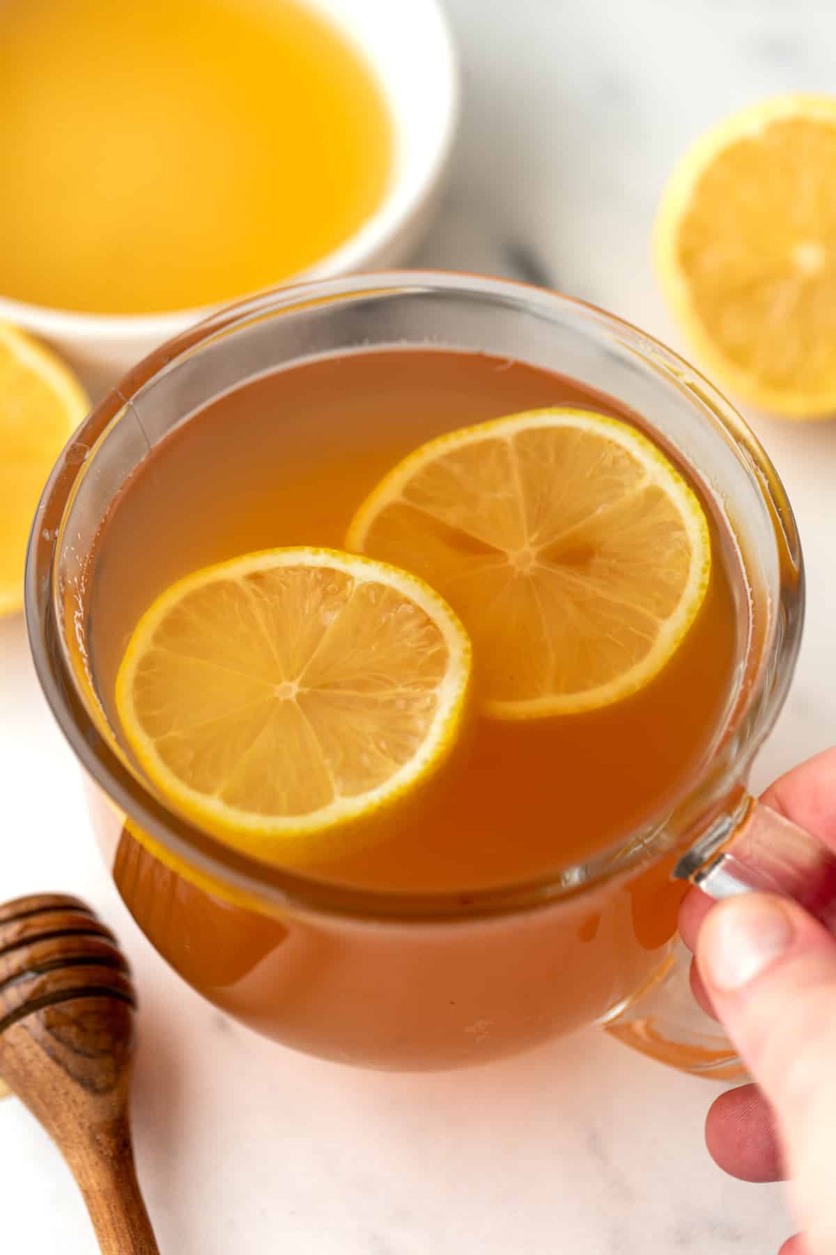 A glass mug filled with tea and garnished with fresh lemon slices.