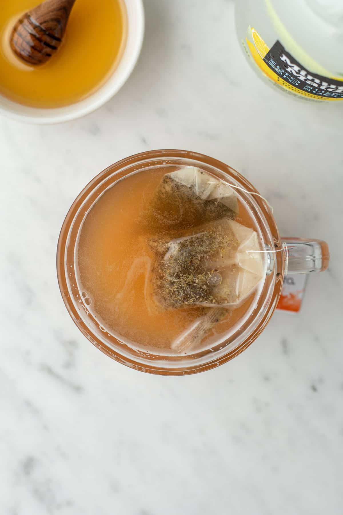 Steeped tea that has an orange-ish hue in a glass mug.