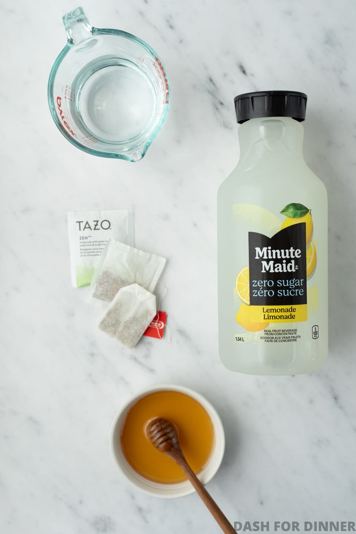 The ingredients needed to make medicine ball tea, including lemonade, honey, tea, and water.