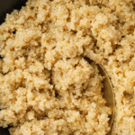 A bowl of quinoa with a spoon scooping a small portion.