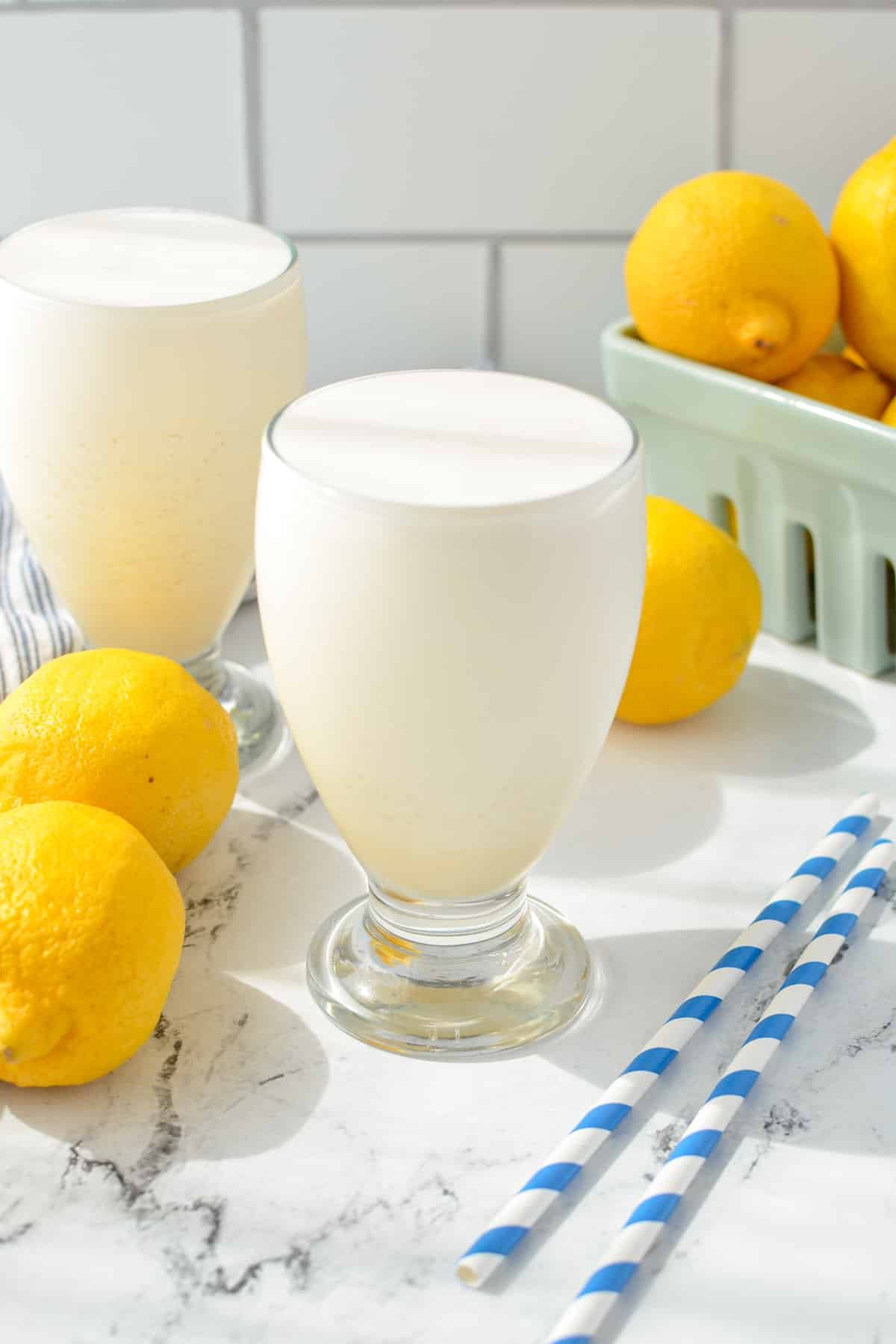 A tall glass of protein lemonade with lemons in the background.