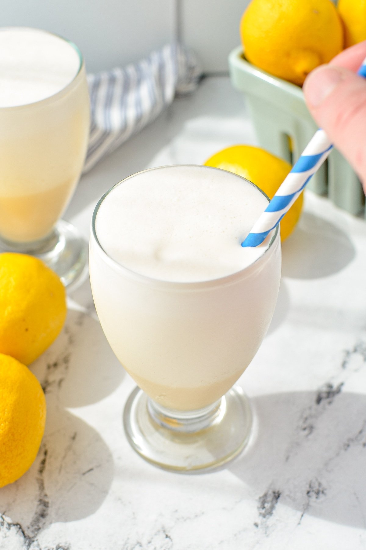 Stirring a straw into a class of creamy lemonade.