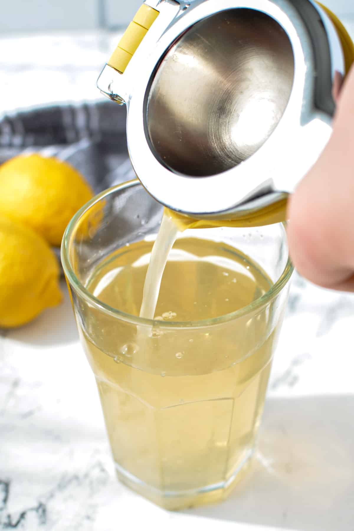 Pouring lemon juice into a glass with water.