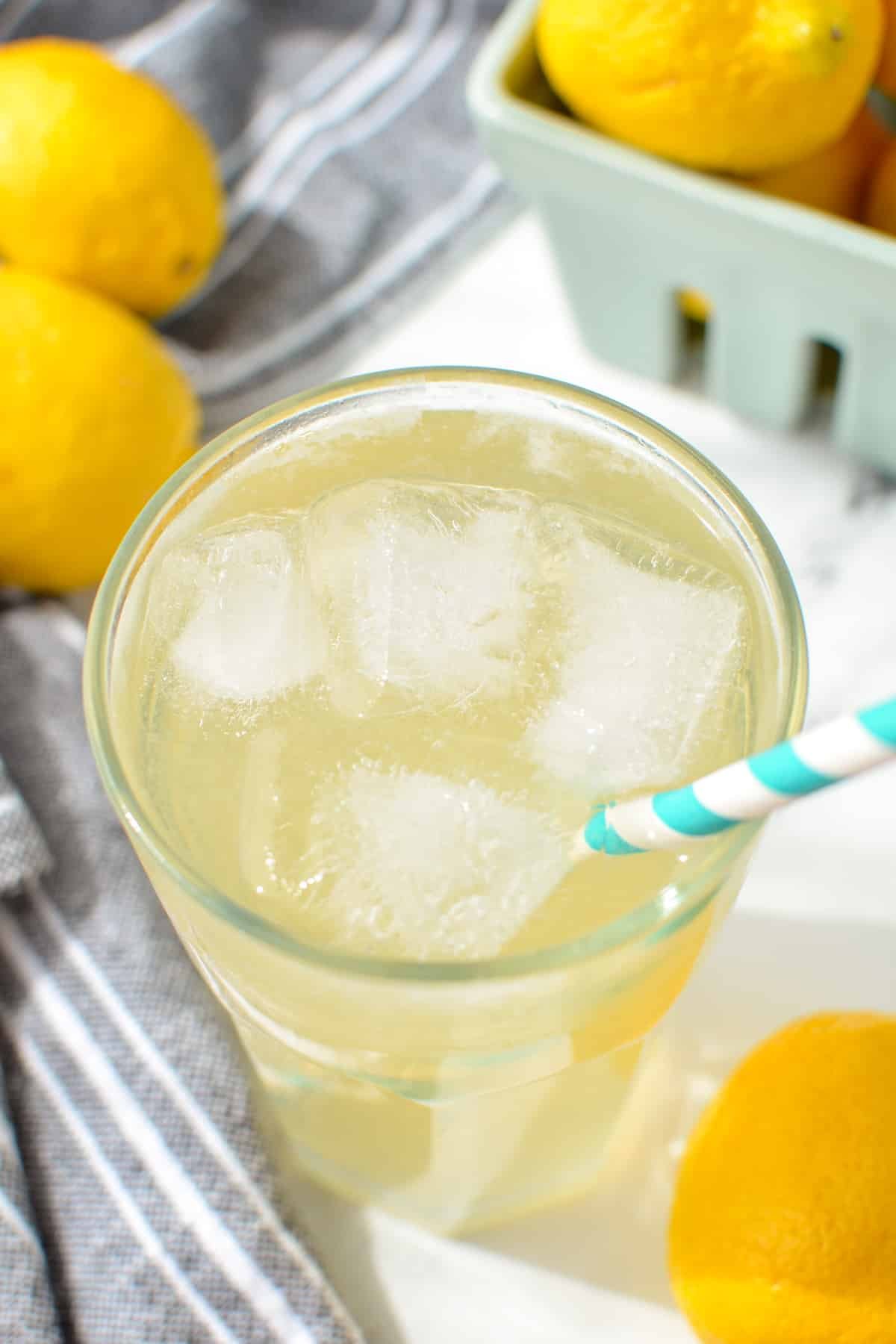 A glass of lemonade with a paper straw sticking out.