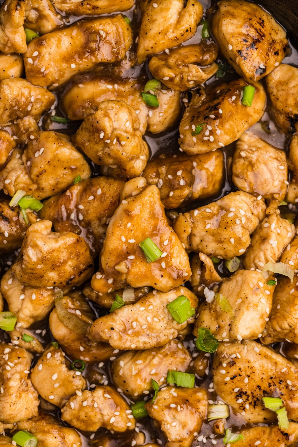 A close up on cubed cooked chicken that's been cooked in a golden sauce.