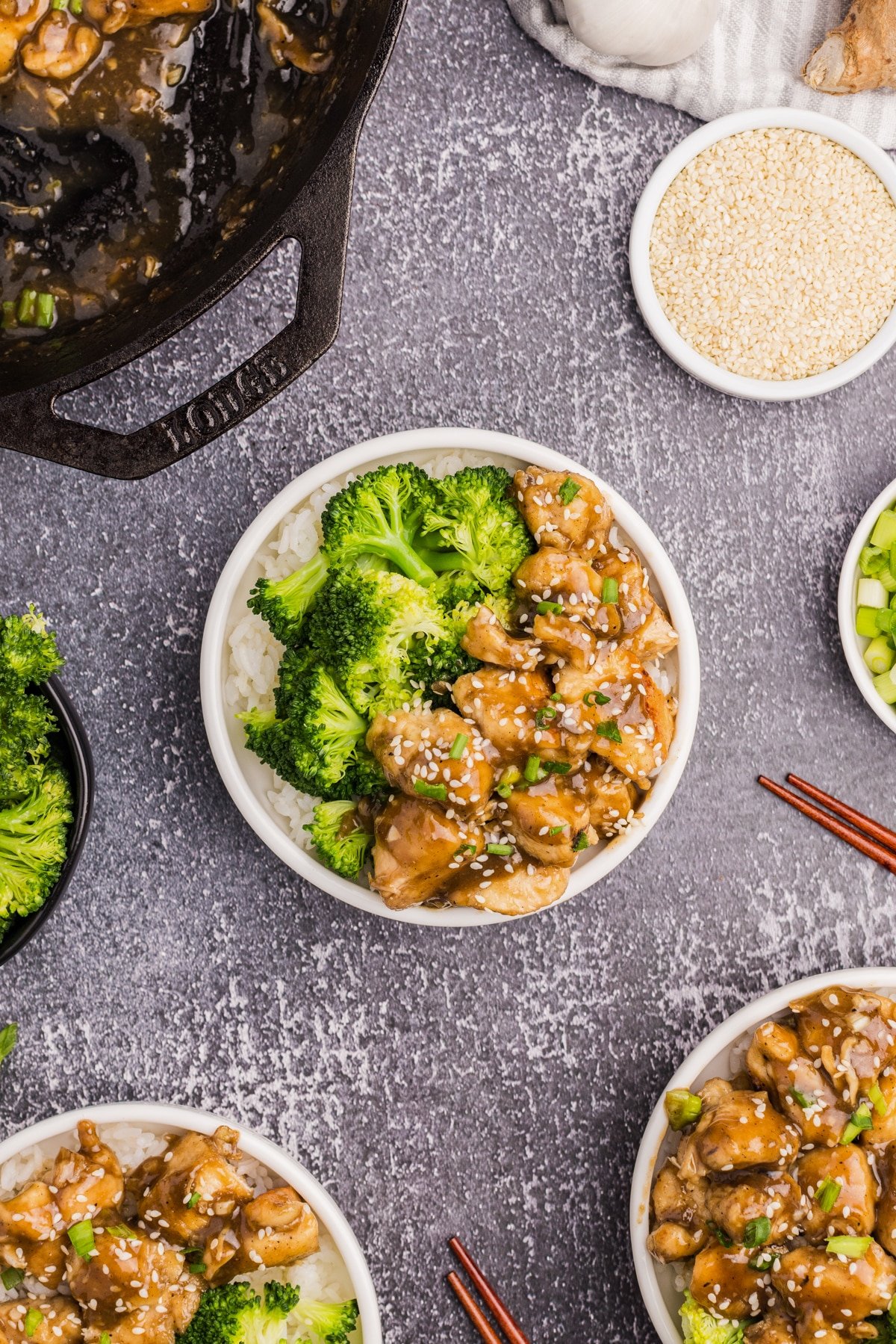 A bowl with broccoli and chicken stir fry, with several small bowls surrounding the outer frame.