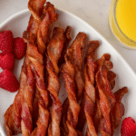 A platter featuring a pile of twisted bacon slices that have been cooked until crisp.