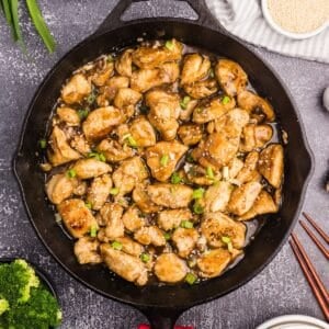A skillet filled with cooked chicken stir fry with a golden sauce.