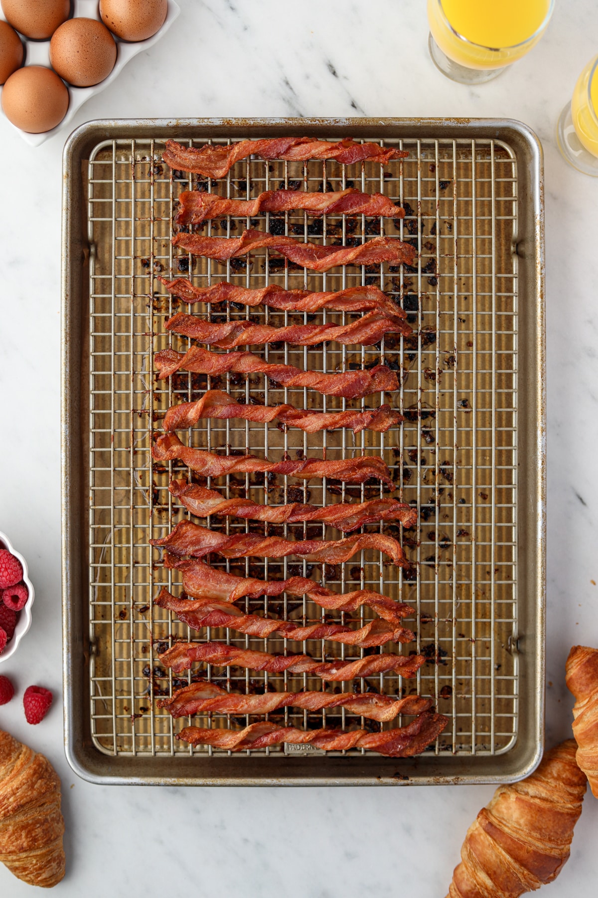 A baking sheet filled with crispy twisted bacon slices.