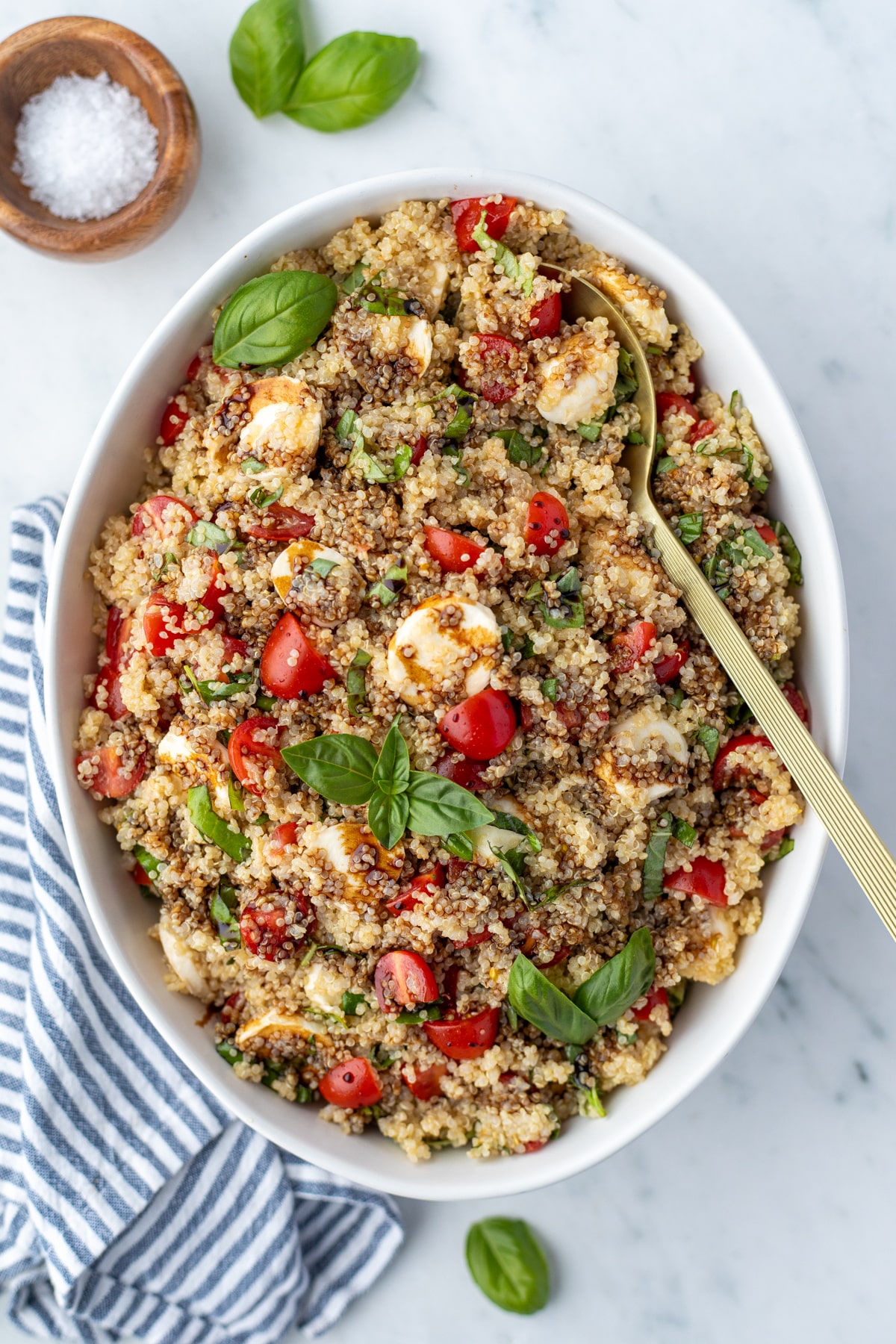 A bowl of quinoa salad garnished with fresh basil and a drizzle of balsamic glaze.
