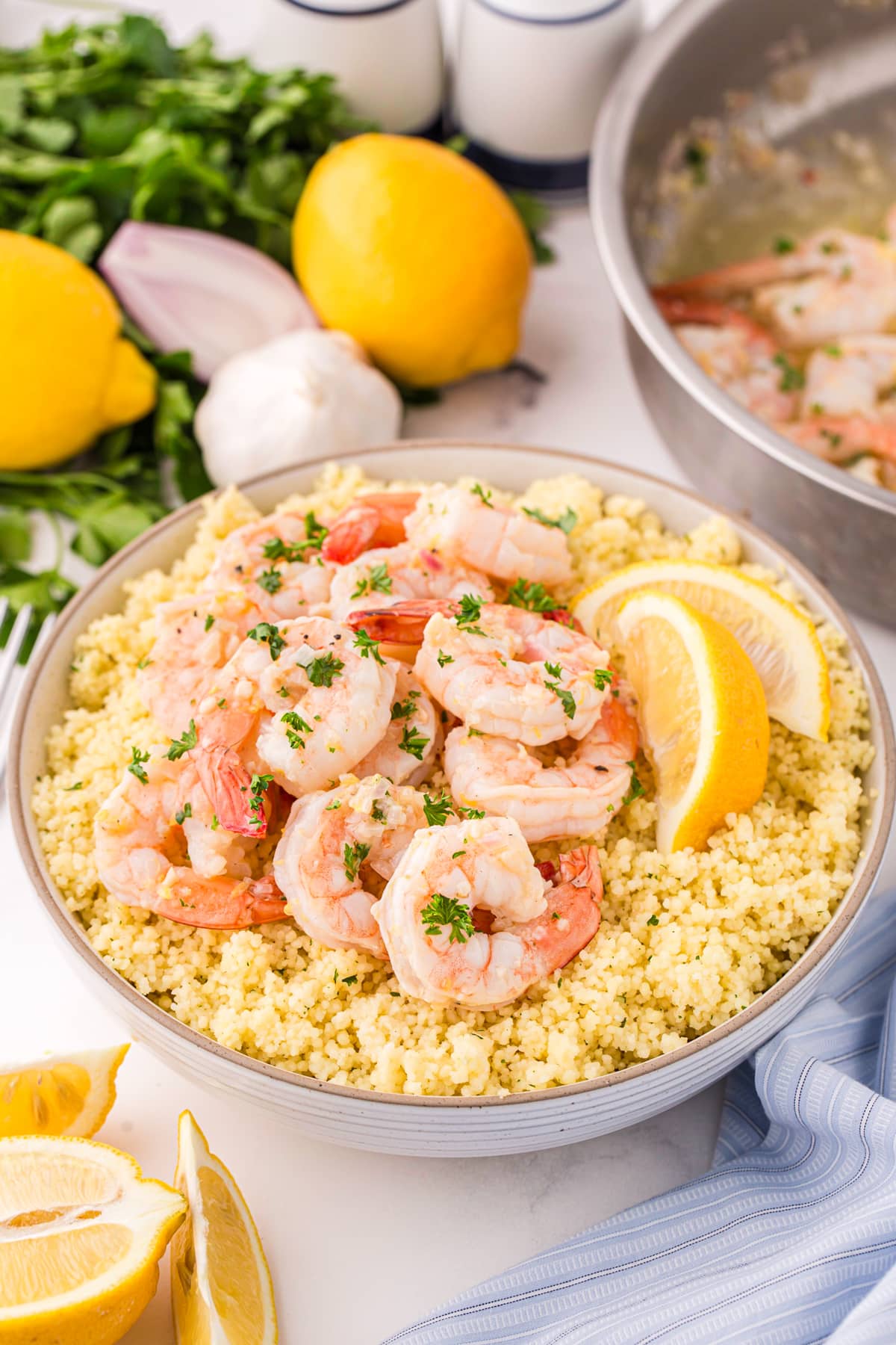 Shrimp on top of a bowl of quinoa and garnished with fresh lemon wedges.