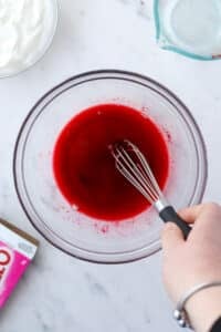 Whisking powdered jello into water in a large bowl.