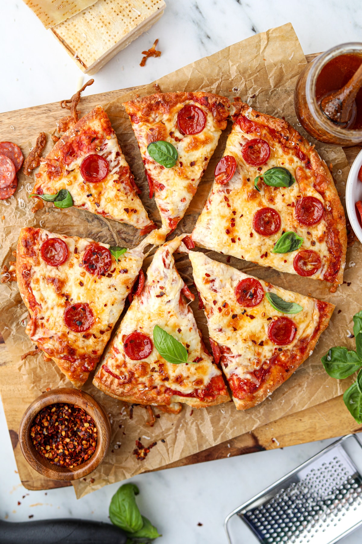 Pizza cut into slices and topped with pepperoni and fresh basil.