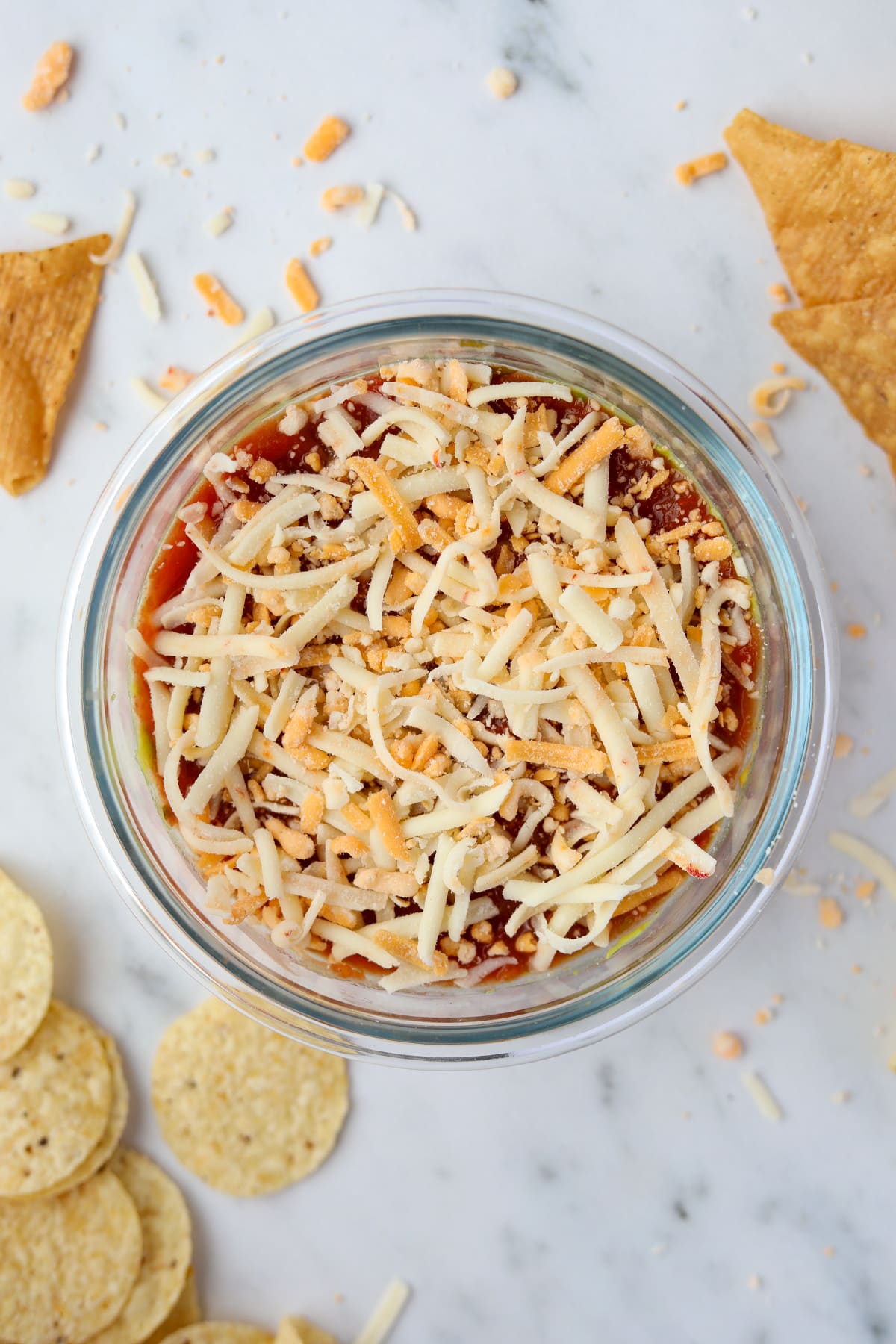 A small bowl filled with a single serving dip featuring salsa and shredded cheese.