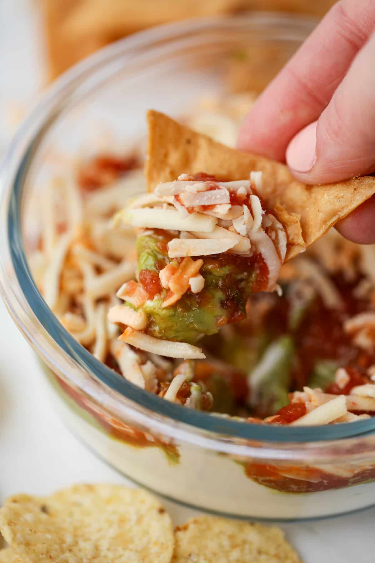 Dipping a tortilla chip into a cheese and salsa based dip.