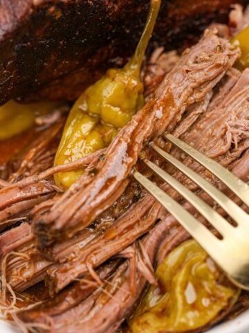 A fork spearing shreds of pot roast covered in juices.